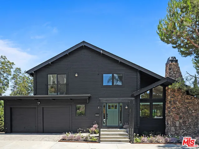 a front view of a house with a tree