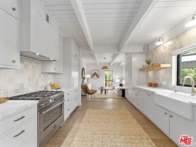 a kitchen with stove a sink dishwasher and white cabinets with wooden floor