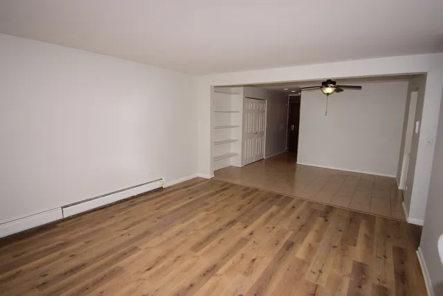 a view of a room with wooden floor and a ceiling fan
