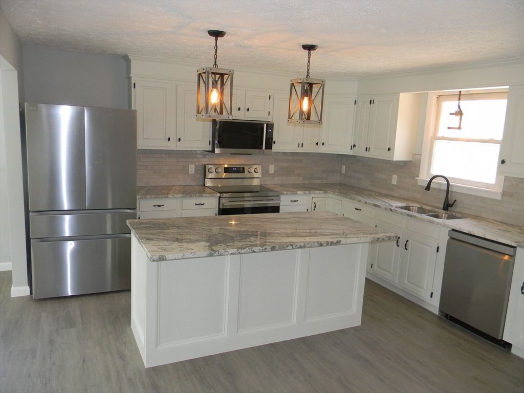 1 Lenox Street Athol, MA 01331 - Photo 5 of 37 a kitchen with stainless steel appliances granite countertop a sink a refrigerator a microwave a stove and white cabinets