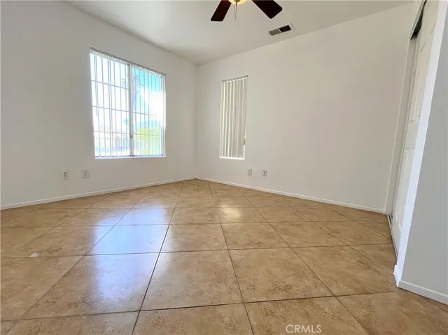 a view of an empty room with windows and ceiling fan