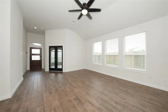 a view of an empty room with a window and wooden floor
