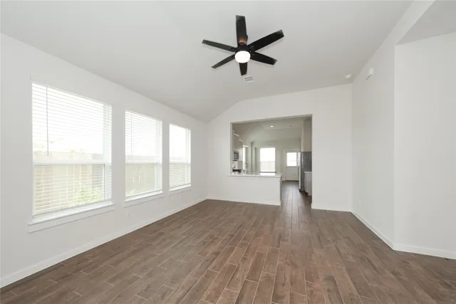 a view of empty room with wooden floor and fan