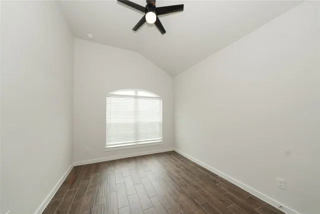 an empty room with wooden floor cabinet and windows