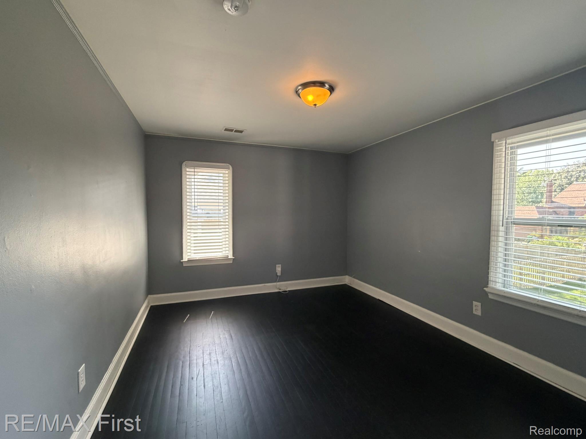 1349 Devonshire Road Grosse Pointe, MI 48230 - Photo 26 of 31 Spacious bedroom featuring dark wood-finish flooring, soft-close electrical outlets, and a two-tone paint scheme with crisp white chair rail trim
