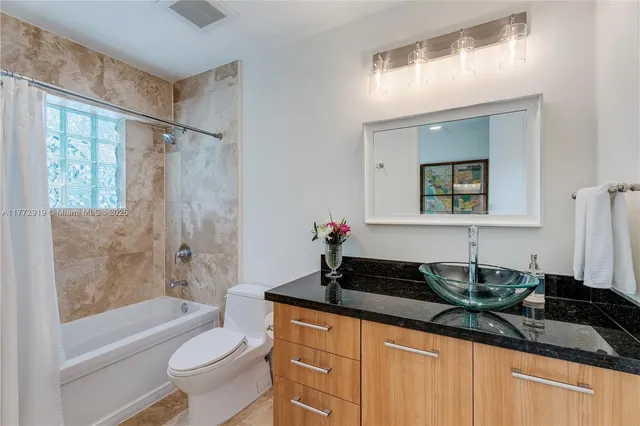 a bathroom with a granite countertop sink a toilet a mirror and shower