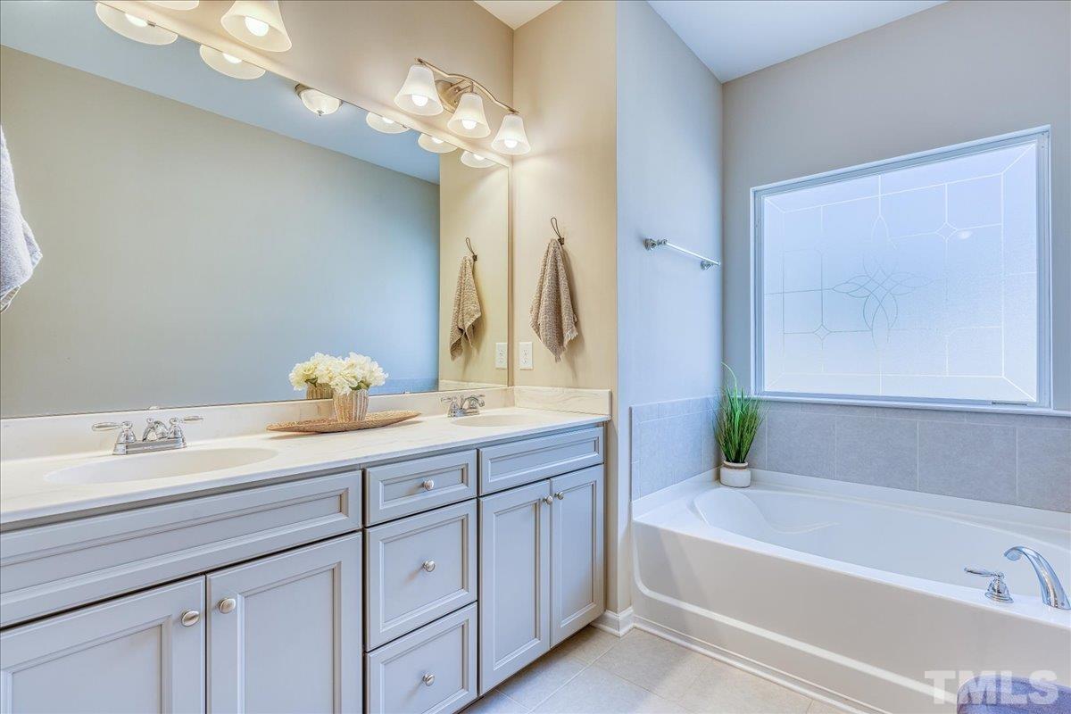 6328 Grace Lily Drive Raleigh, NC 27607 - Photo 21 of 27 a bathroom with a tub a sink and a large mirror