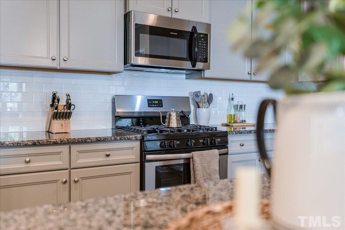 6328 Grace Lily Drive Raleigh, NC 27607 - Photo 4 of 27 a kitchen with stainless steel appliances granite countertop a stove a microwave and cabinets