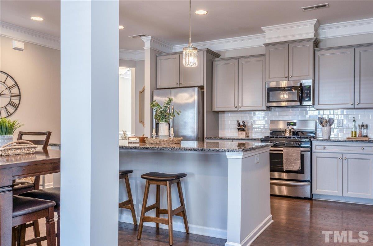 6328 Grace Lily Drive Raleigh, NC 27607 - Photo 5 of 27 a kitchen with kitchen island granite countertop wooden cabinets and a stove