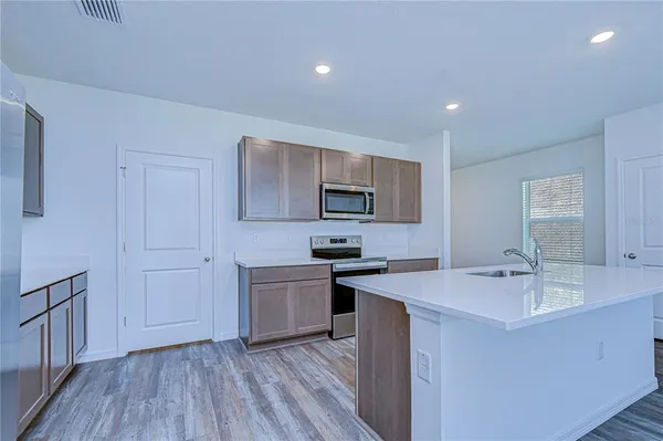 a view of an empty room with wooden floor kitchen and windows