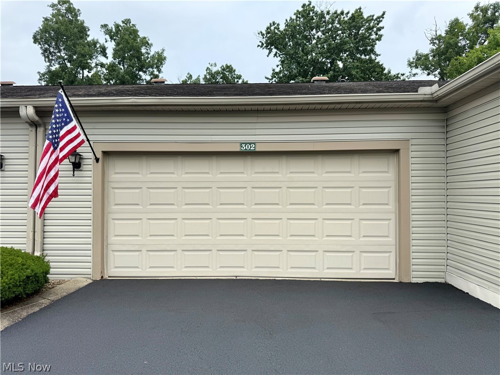 302 Wilcox Road Youngstown, OH 44515 - Photo 3 of 30 Attached single-car garage with paneling, asphalt driveway, and exterior wall lighting