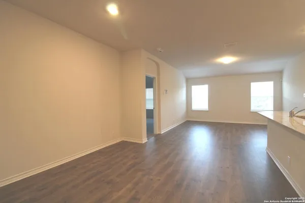 a view of an empty room with wooden floor and window