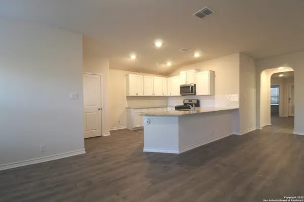 a view of kitchen with kitchen island wooden floor center island and stainless steel appliances