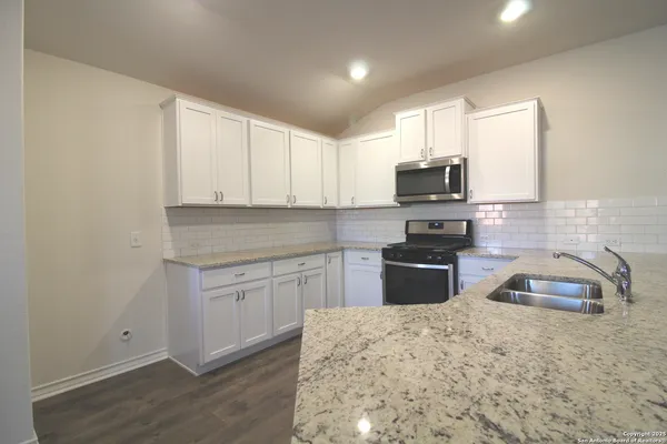 a kitchen with kitchen island a stove a sink and a microwave