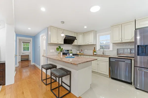 a kitchen with stainless steel appliances granite countertop a sink a stove a refrigerator cabinets and chairs