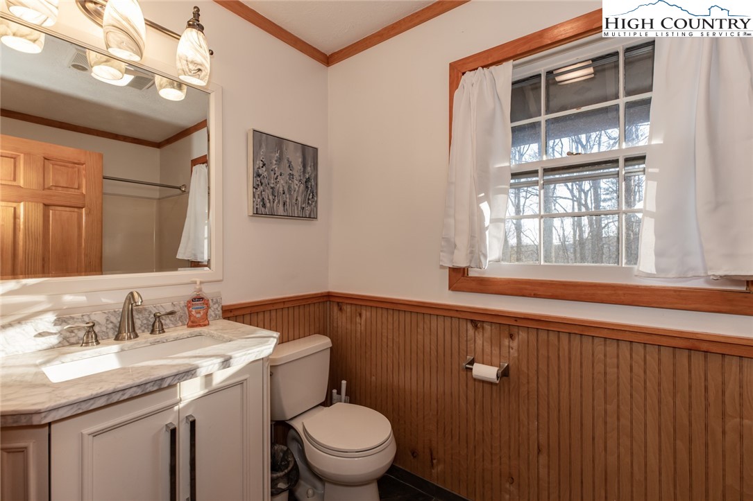 107 Buckshot Ridge Road Deep Gap, NC 28618 - Photo 23 of 30 a bathroom with a granite countertop sink a toilet and a window