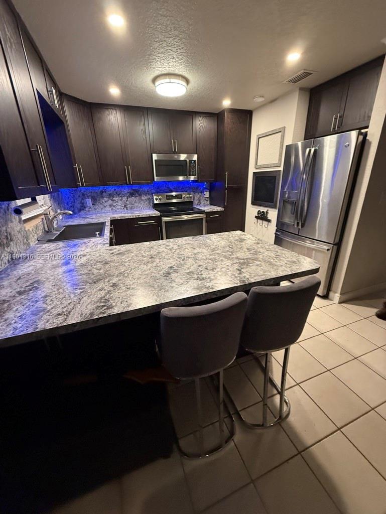 9546 Southwest Adams Avenue Okeechobee, FL 34974 - Photo 3 of 16 a kitchen with stainless steel appliances kitchen island granite countertop a sink refrigerator and cabinets