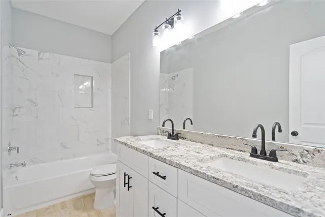 a bathroom with a granite countertop sink a toilet and bathtub