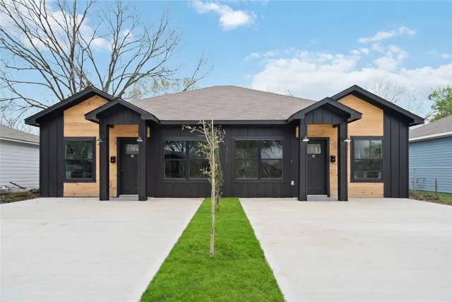 a view of a white house with a small yard and potted plants