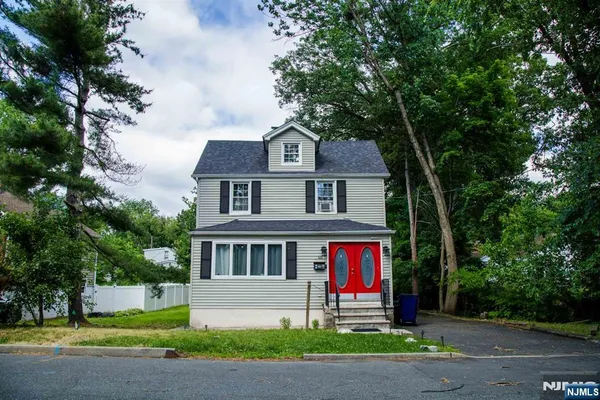 a front view of a house with garden and trees