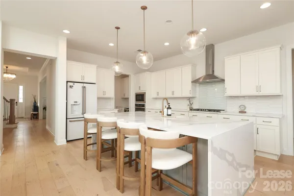 a large kitchen with cabinets chairs and stainless steel appliances