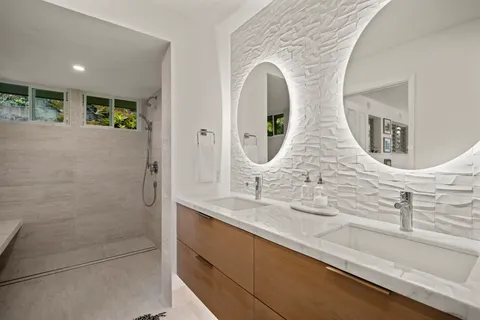 a en suite bathroom with a granite countertop sink a mirror and shower