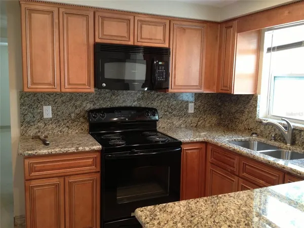 a kitchen with granite countertop a sink stove and microwave