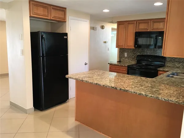 a kitchen with granite countertop a refrigerator and a stove top oven