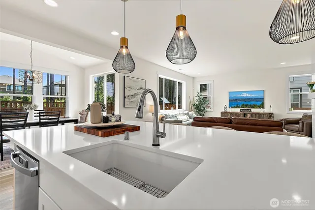 a kitchen with stainless steel appliances granite countertop a sink dishwasher a dining table and chairs with wooden floor