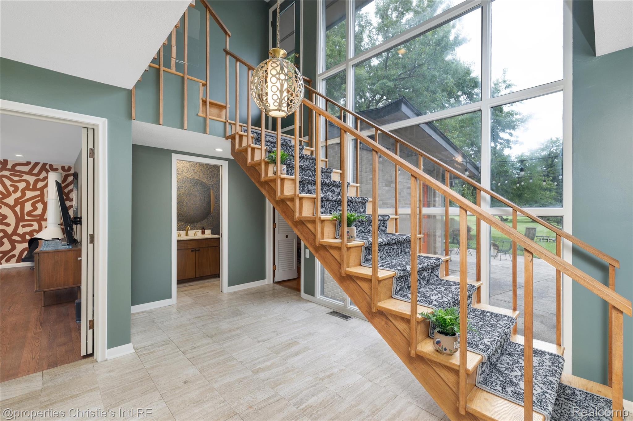 2771 West Seven Mile Road Detroit, MI 48221 - Photo 35 of 57 Two-story entry foyer featuring a natural wood staircase with patterned carpet runner, expansive floor-to-ceiling windows, and a decorative pendant light fixture