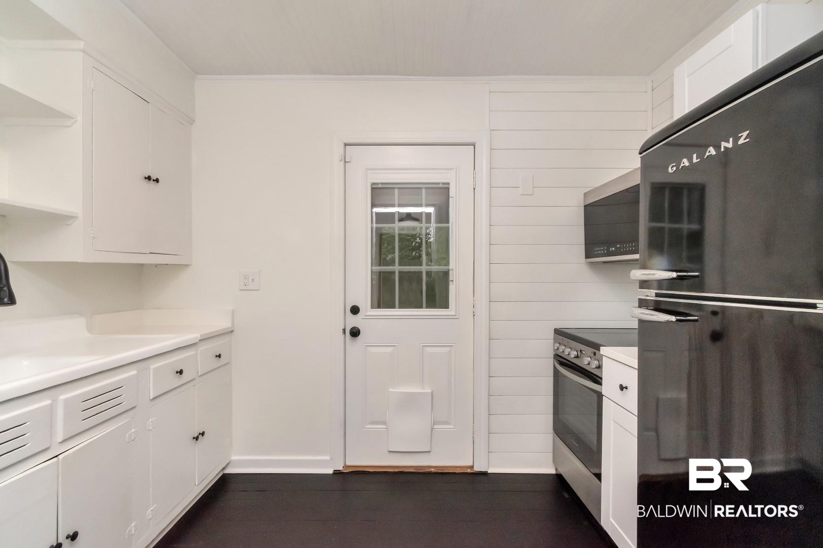 208 Morgan Avenue Mobile, AL 36606 - Photo 10 of 27 Kitchen with wood walls, dark wood-type flooring, stainless steel appliances, and white cabinets