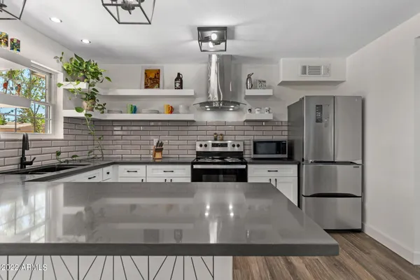 a kitchen with stainless steel appliances granite countertop a stove a sink and a refrigerator