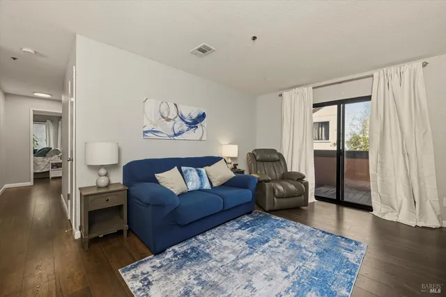 a living room with furniture a wooden floor and a large window