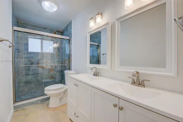 a bathroom with a sink a toilet a mirror and shower