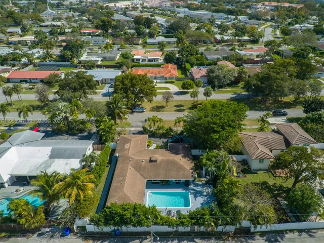 an aerial view of residential houses with outdoor space and trees