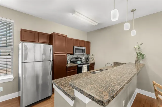 a kitchen with stainless steel appliances granite countertop a refrigerator a stove and a sink