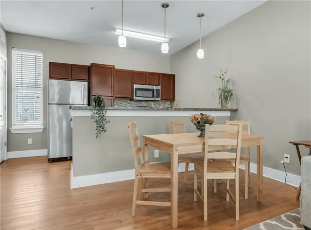 a kitchen with stainless steel appliances a dining table chairs refrigerator and microwave