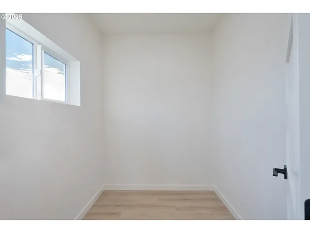 a view of an empty room with wooden floor and windows