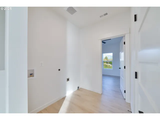 a view of an empty room with a window and wooden floor