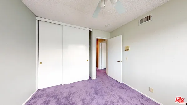 an empty room with windows and ceiling fan