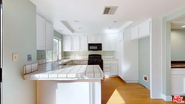 a kitchen with granite countertop white cabinets sink and stainless steel appliances