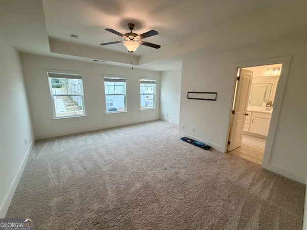 an empty room with windows and fan