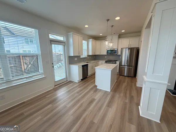 a kitchen with a refrigerator a sink and wooden floor