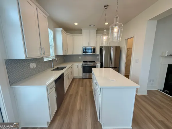 a kitchen with a sink a kitchen island a stove a refrigerator cabinets and a dining table