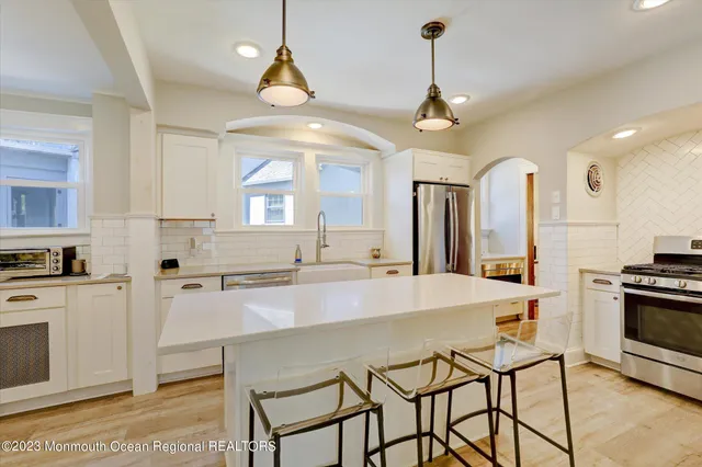 a kitchen with stainless steel appliances a dining table chairs stove and sink