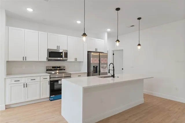 a large kitchen with stainless steel appliances kitchen island a cabinets and wooden floor