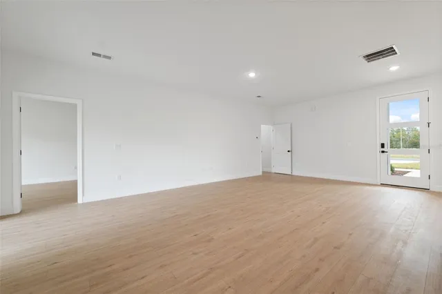 a view of an empty room with wooden floor and a sink