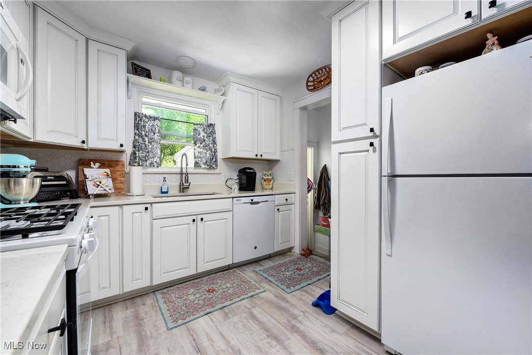 3615 Kolbe Road Lorain, OH 44053 - Photo 11 of 33 Kitchen featuring light wood-type flooring, tasteful backsplash, white cabinets, sink, and white appliances