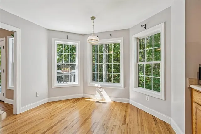 a view of an empty room with a window and wooden floor