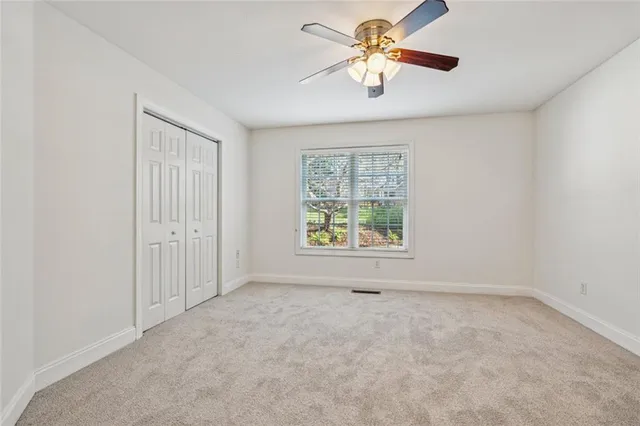 an empty room with windows and chandelier fan